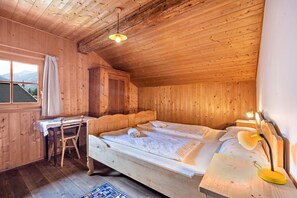 Une chambre dans un chalet en bois, avec un lit, un bureau et une fenêtre donnant sur les montagnes.