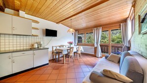A wooden ceiling, a kitchen with white cabinets, a dining table with chairs, a sofa, and a window with curtains. - Mayrhof Ahorn Apartment with Mountain View, Wi-Fi & Balcony (St. Pankraz)