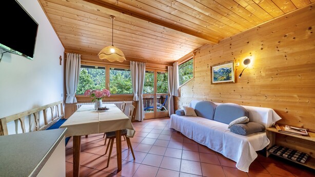 A wooden interior with a dining table, sofa, and a painting on the wall. - Mayrhof Ahorn Apartment with Mountain View, Wi-Fi & Balcony (St. Pankraz)