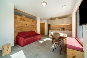 Ein modernes Interieur mit einem roten Sofa, Holzelementen, einem Essbereich und einer Küche.