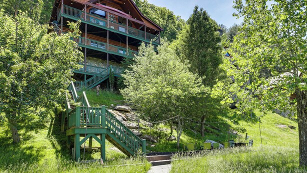 A multi-story log cabin with a balcony, surrounded by lush greenery and a stone staircase. - 'River Dream Cabin' on New River w/ Fire Pit (Piney Creek)