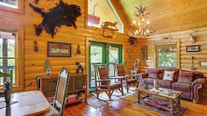 A log cabin interior with a wooden floor, a sofa, rocking chairs, a coffee table, and a chandelier. - 'River Dream Cabin' on New River w/ Fire Pit (Piney Creek)