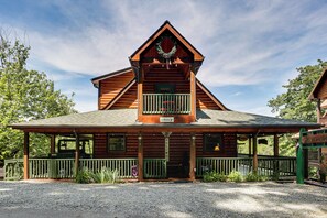 A wooden lodge with a balcony, a porch, and a sign that reads 'Welcome.'
