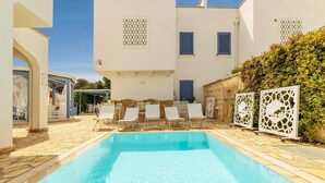 A swimming pool with white lounge chairs and a stone-tiled deck. - Appartamento Playa Iside - Torre... (Torre lapillo)