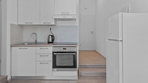 A modern kitchen with white cabinetry, a built-in oven, a sink, and a refrigerator.
