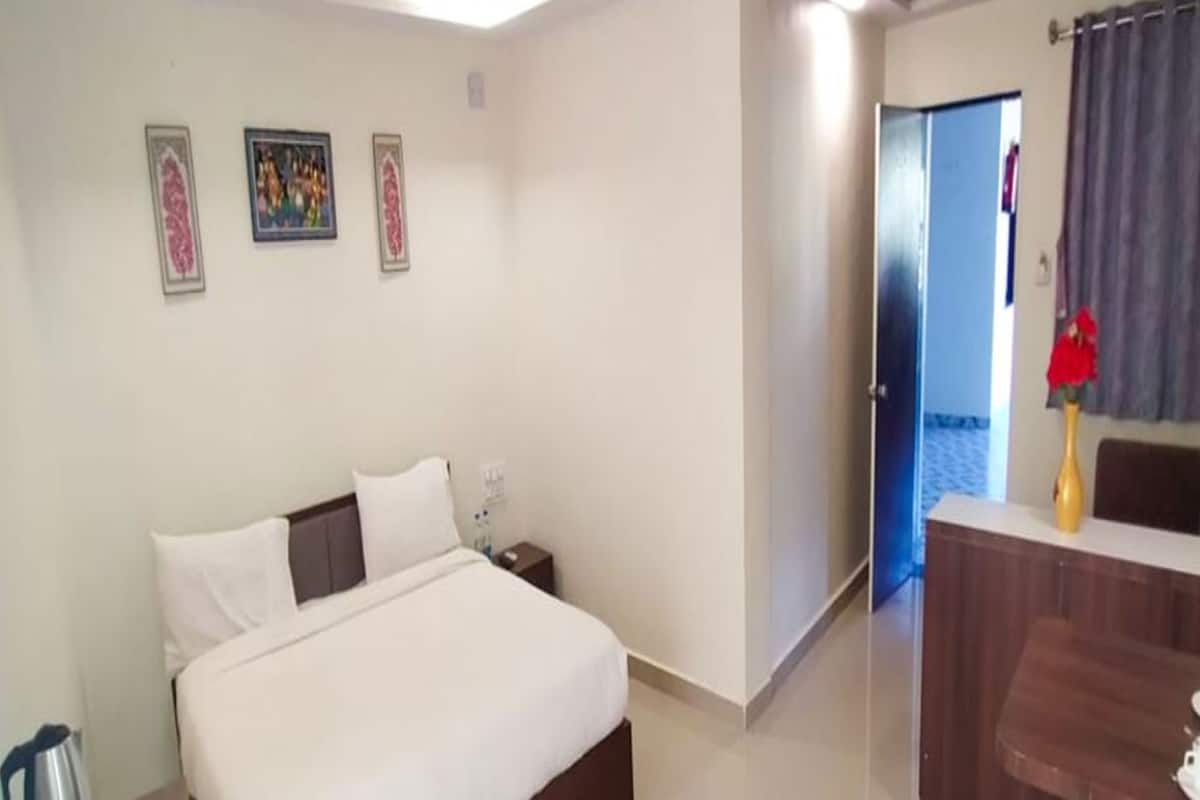 Quarto de hotel com cama, mesa de cabeceira e escrivaninha com cadeira.