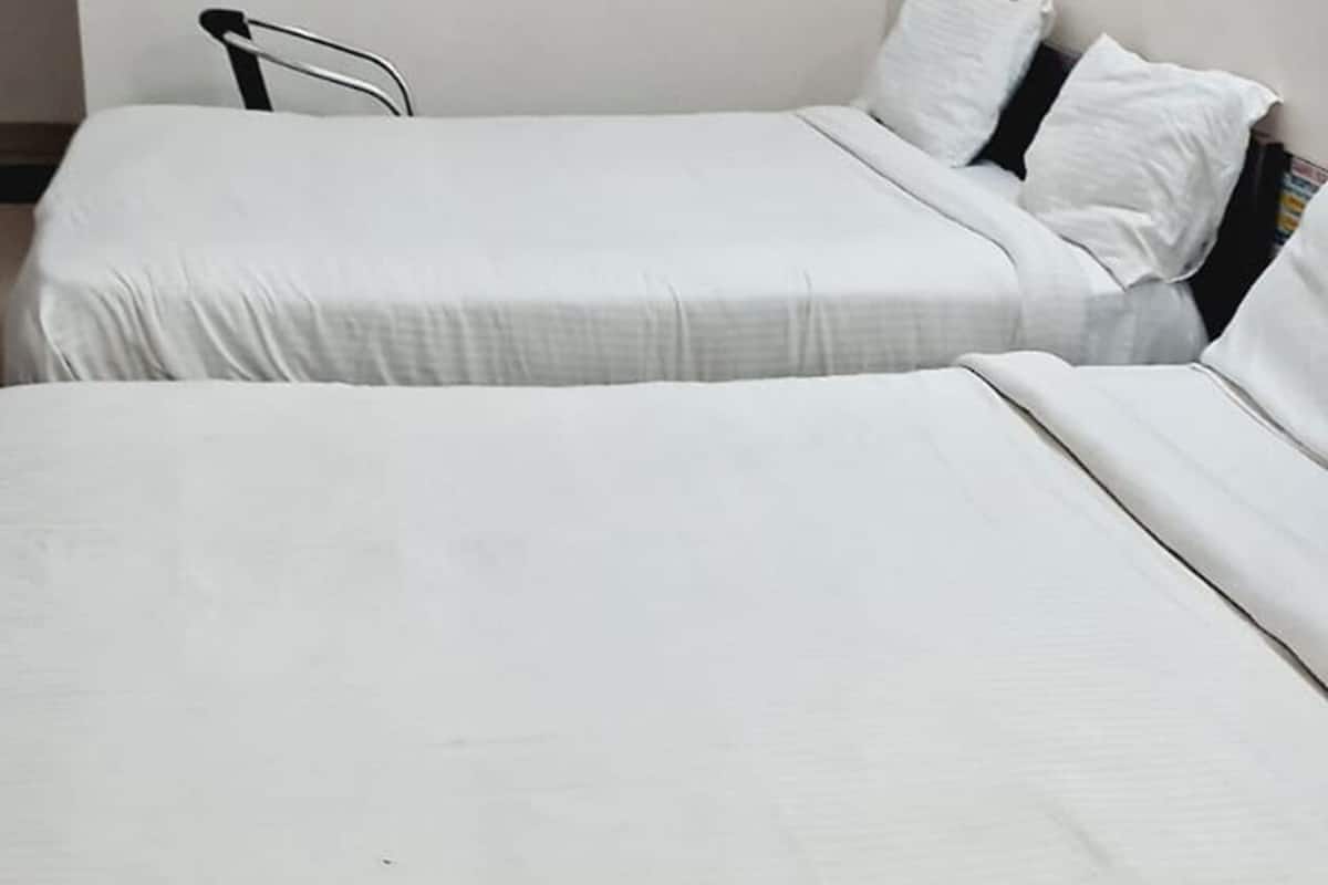 Quarto com duas camas de solteiro, cada uma com roupa de cama branca e cabeceira de madeira.