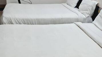 Una habitación con dos camas individuales, cada una con ropa blanca y cabeceros de madera.