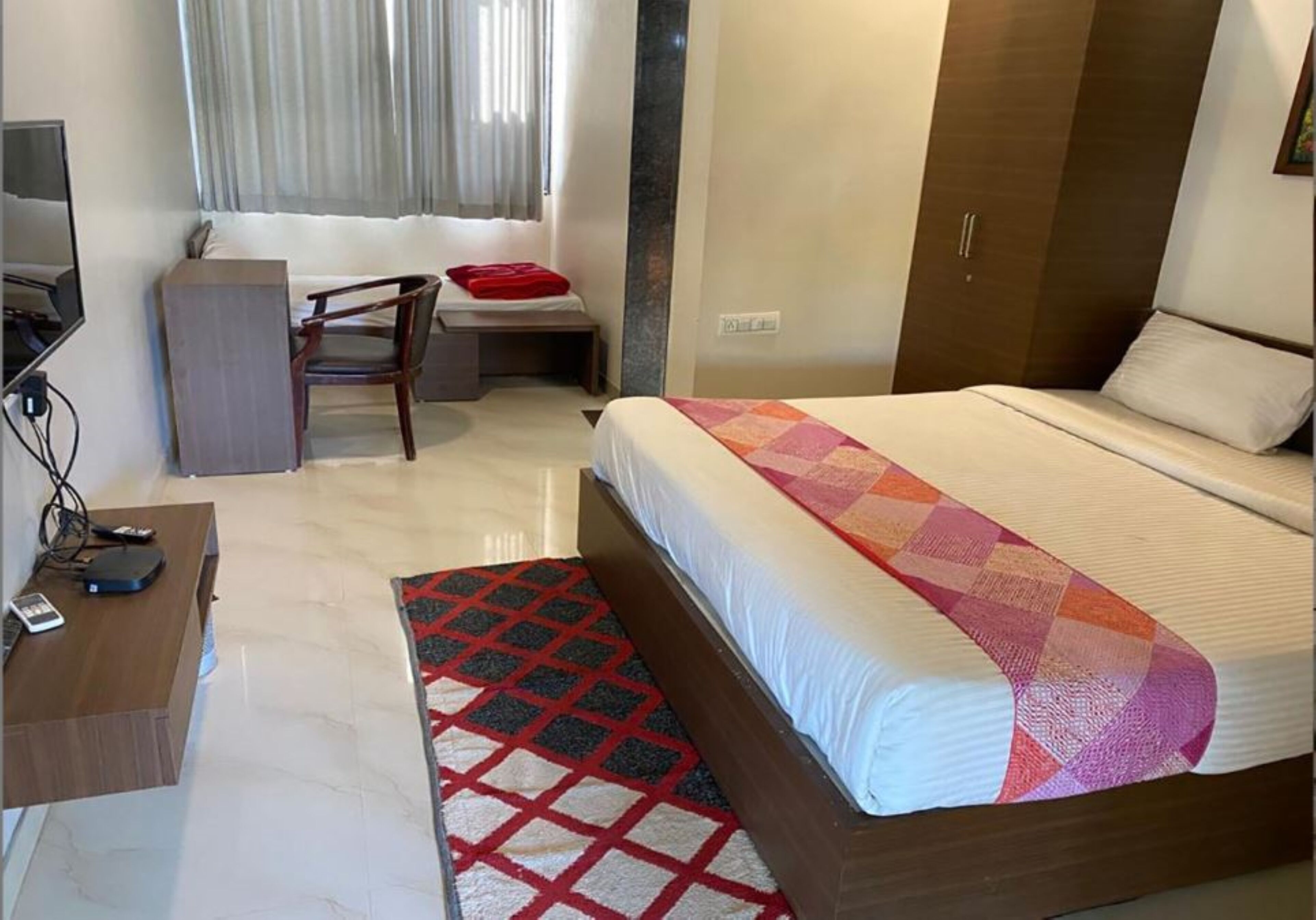 Habitación de hotel con cama, escritorio, silla y televisión.