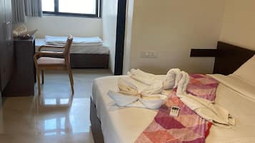 Una habitación de hotel con una cama, un escritorio, una silla y una ventana.