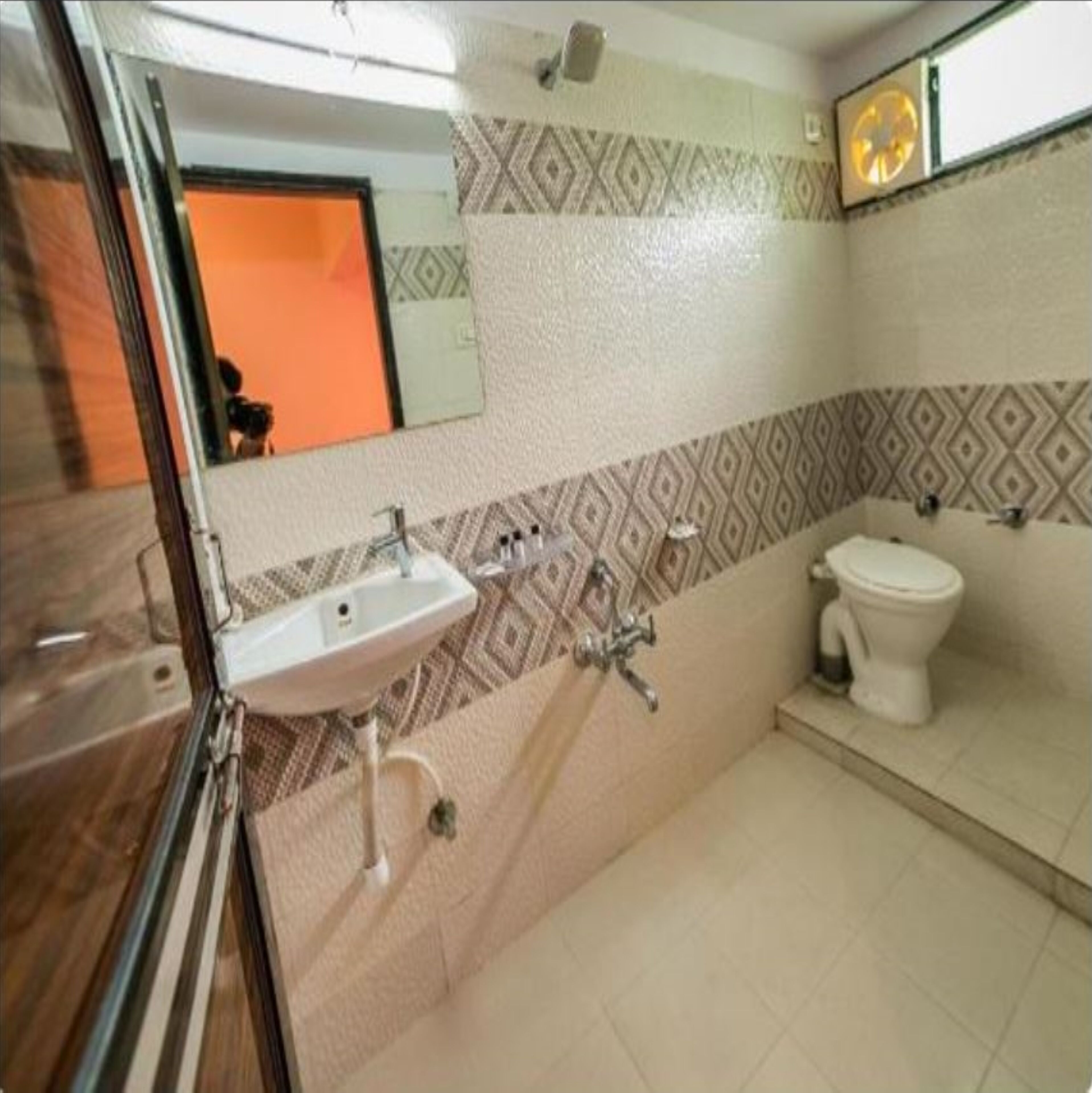 A bathroom with a sink, toilet, and a mirror.