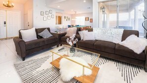 A modern living room with two brown sofas, a glass coffee table, and a white shag rug.