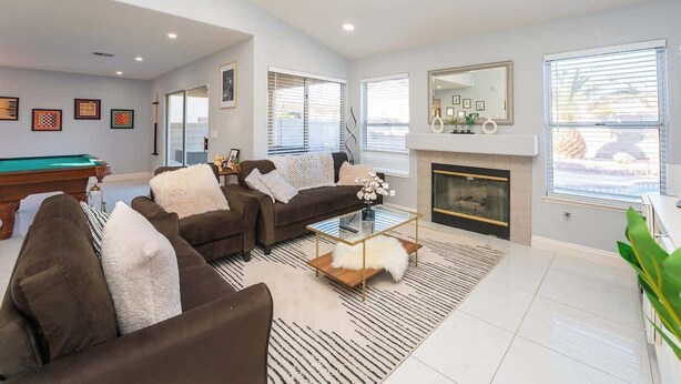 A modern living room with a pool table, two sofas, a coffee table, and a fireplace.