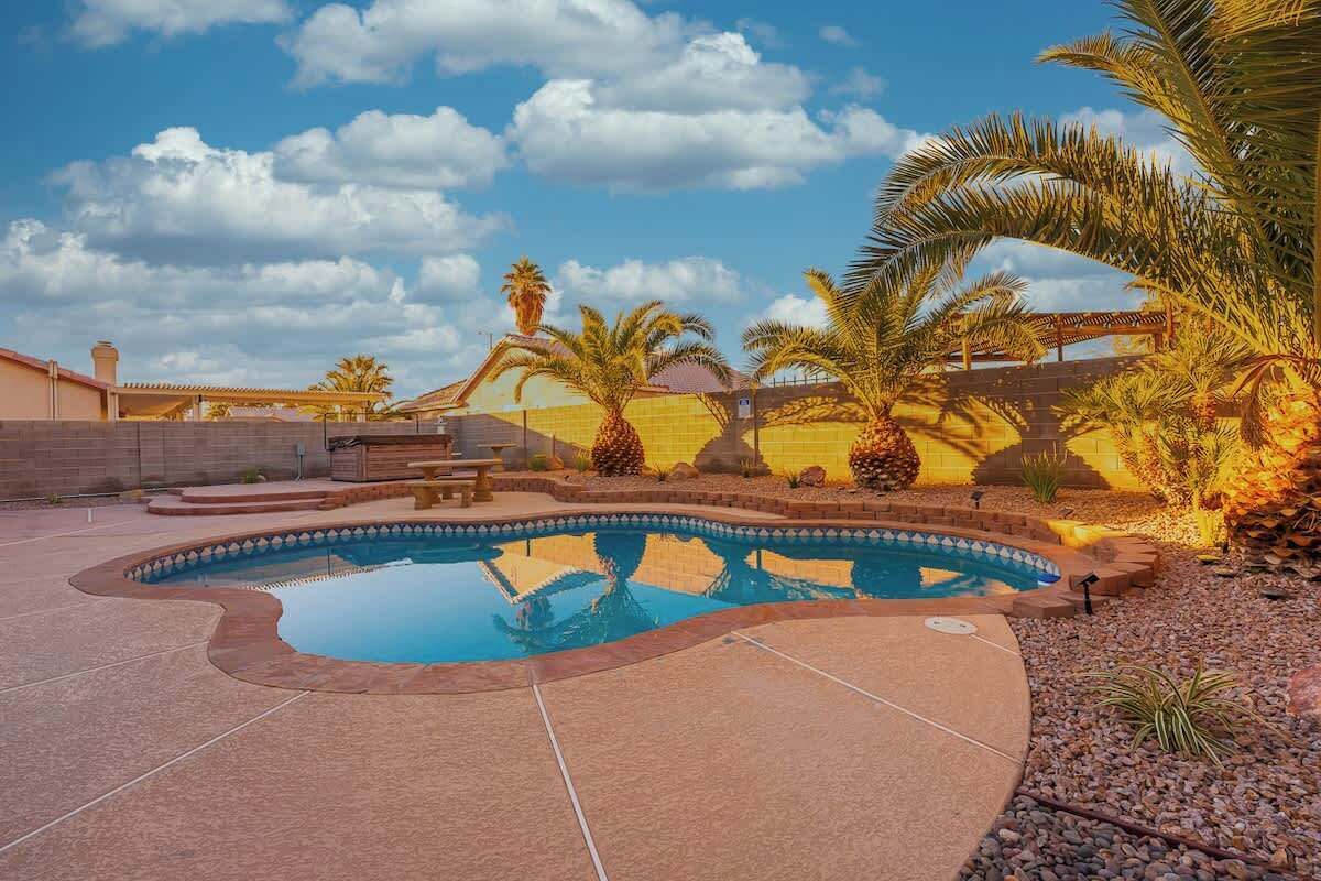 A swimming pool with a curved edge, surrounded by a patio area with a brick border.