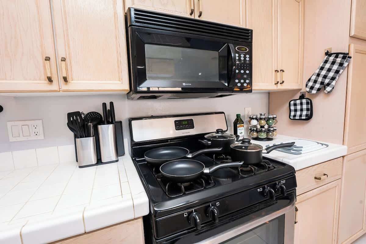 Una cocina con microondas, estufa y diferentes utensilios.