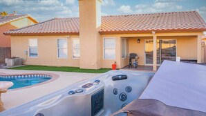 A residential house with a swimming pool, a hot tub, and a patio area.