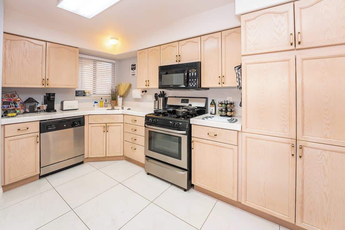 A modern kitchen with light wooden cabinets, stainless steel appliances, and a central island.