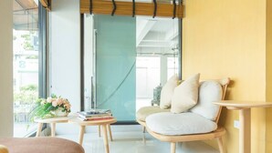 Une pièce moderne avec un canapé, une petite table ronde agrémentée de livres et de fleurs, et un arbre à chat.