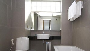Une salle de bain comprenant des toilettes, un lavabo, un miroir et une baignoire.