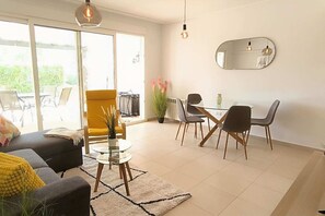 Ein modernes Wohnzimmer mit einer Couch, einem Couchtisch und einem Essbereich mit Stühlen und einem Tisch.