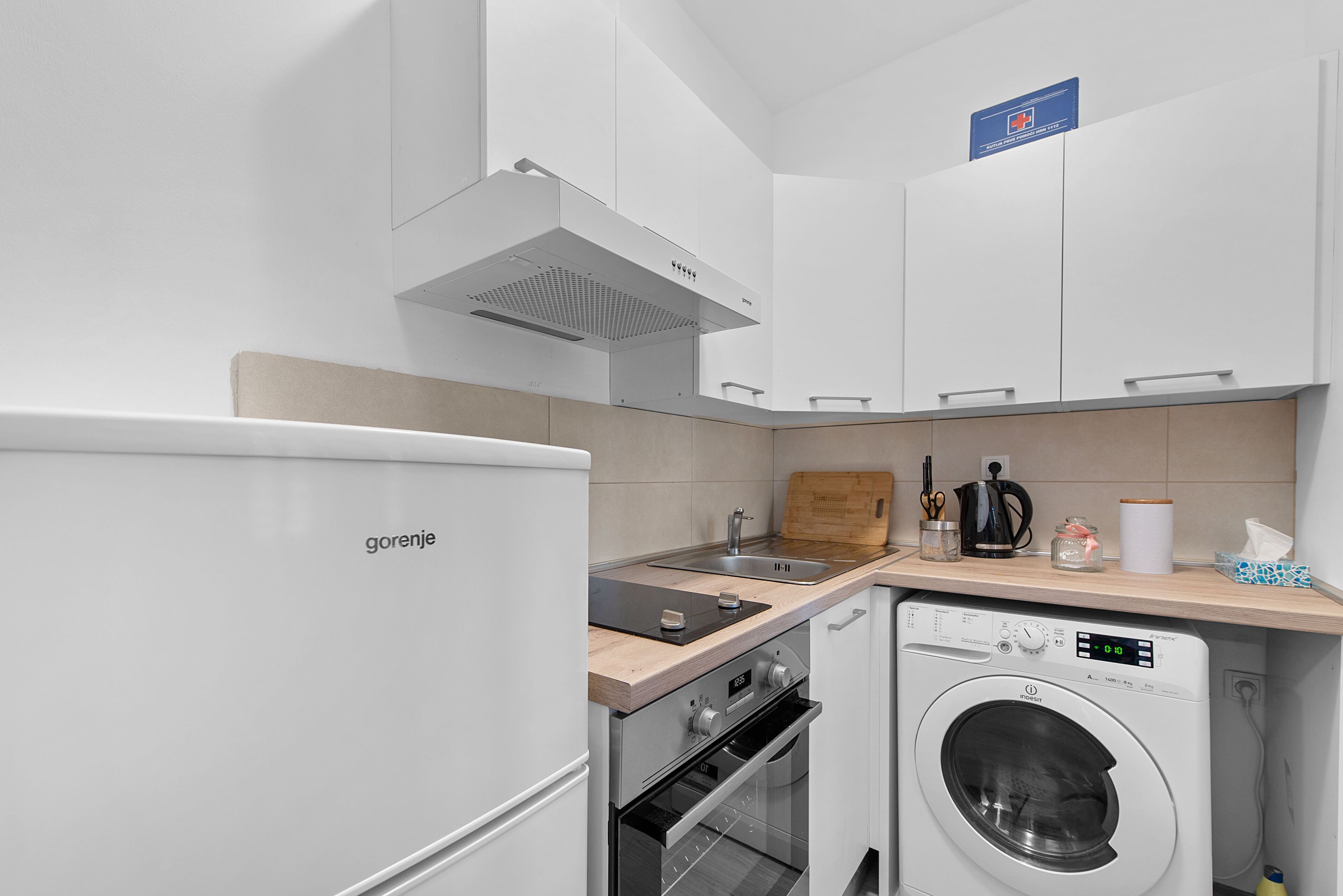 A modern kitchen with a built-in oven, a washing machine, and a sink.