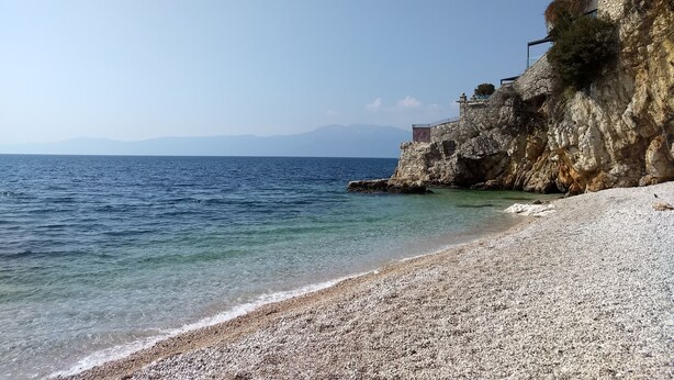 A pebble beach with clear water and a rocky cliff. - La Guardia apartments (Rijeka)