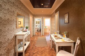 A hotel room with a wooden herringbone floor, a dining area with a table set for breakfast, and a mirror on the left wall. - Sun Spalato Beach (Split)
