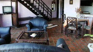 Una sala de estar con escaleras, muebles de cuero y un comedor.