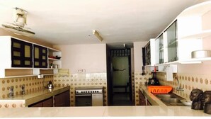 Una cocina con estufa a gas, horno y microondas. Hay armarios y un lavamanos.