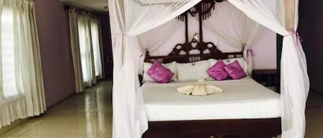 A four-poster bed with a canopy, white bedding, and purple pillows.
