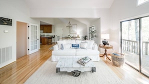 A spacious living room with a white sofa, a coffee table, and a view of the kitchen and dining area. - Private Cove + Dock, Kayaks, Paddleboards, Fire Pit,  Pet-Friendly Lake Escape (Smith Mountain Lake Virginia)