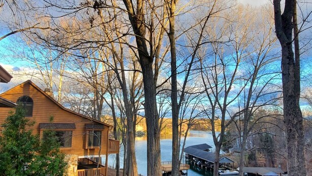 A cabin with a deck overlooking a lake, surrounded by trees. - Private Cove + Dock, Kayaks, Paddleboards, Fire Pit,  Pet-Friendly Lake Escape (Smith Mountain Lake Virginia)