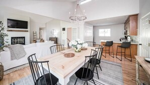 A spacious living room with a wooden dining table, black chairs, and a chandelier. - Private Cove + Dock, Kayaks, Paddleboards, Fire Pit,  Pet-Friendly Lake Escape (Smith Mountain Lake Virginia)