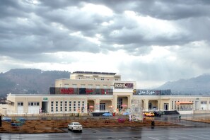 A hotel with a large sign, multiple windows, and a parking lot.