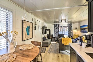 A cozy living area with a sofa, a coffee table, and a dining table. There is a fireplace, a television, and a window with blinds. - Walk to Lake Tahoe: Cozy Zephyr Cove Cabin! (Zephyr Cove)