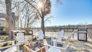 A patio with Adirondack chairs, a fire pit, and a grill.