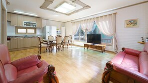 A spacious living room with a dining area, a kitchen, and a TV. - Namhae Capetown (Namhae)