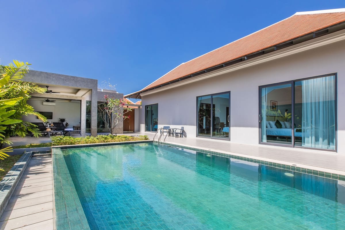 Una casa moderna con piscina, grandes puertas correderas de vidrio y un patio.