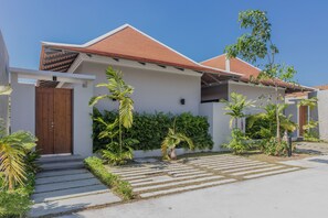 A modern two-story house with a red-tiled roof, a wooden door, and a paved driveway with steps leading to the entrance. - Blu Boat Luxury Pool Villas (Choeng Thale)