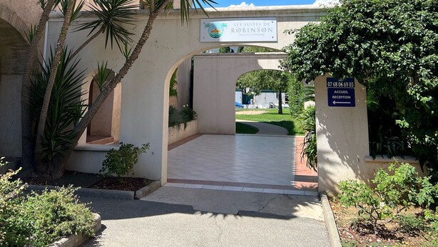 A courtyard with a sign for 'Les Suites de Robinson' and a reception sign. - 3-room apartment near the sea - luxury residence (Mandelieu-la-Napoule)