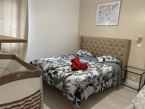 Relax in a cozy retreat with a neatly made bed, framed artwork, and a comfortable chair.