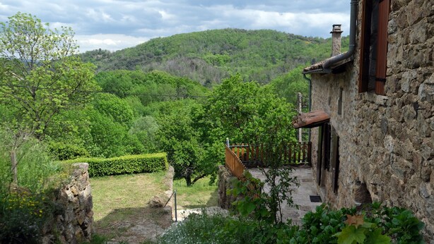 A stone building with a rustic chimney, surrounded by lush greenery and a hillside. - Gîte in an Ardéchois farmhouse in the heart of nature (Fabras)