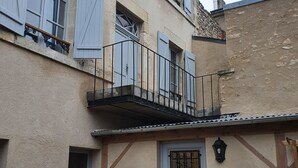 A building with a balcony, a door with a window, and a wall-mounted light fixture.