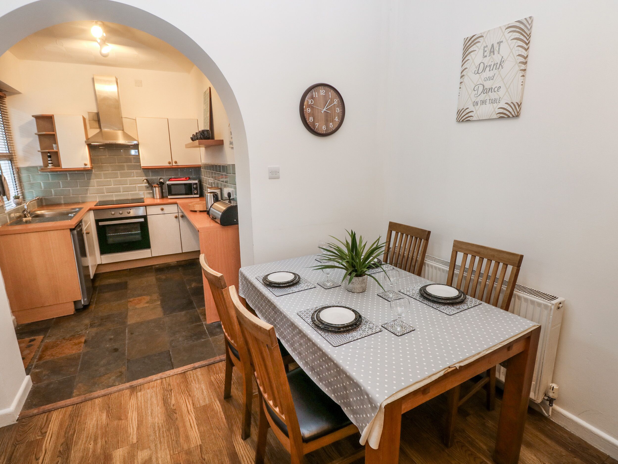 A compact kitchen with modern appliances, a dining table set for four, and a cozy archway leading to the dining area.