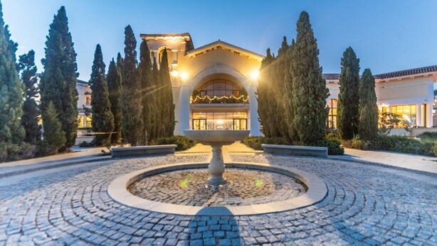A building with a central courtyard, a fountain, and a well-maintained garden with tall trees. - Villa in La Torre Golf Resort. pet friendly (Torre-Pacheco)