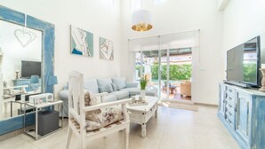 A spacious living room with a sofa, coffee table, and TV. There is a balcony with outdoor furniture. - Villa in La Torre Golf Resort. pet friendly (Torre-Pacheco)