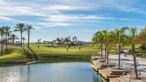 A golf course with a pond, palm trees, and a clear sky. - Villa in La Torre Golf Resort. pet friendly (Torre-Pacheco)