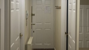 Um corredor com portas brancas, um candelabro e um pequeno armário branco.
