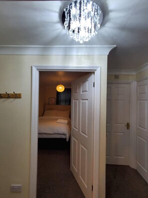 Un dormitorio con cama, candelabro y puerta que da a otra habitación.