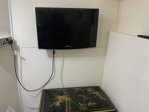 A black flat-screen TV mounted on a white wall, connected to a power outlet.